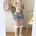 Model wearing a blue ruffled mini skirt, part of the Yume Kawaii Aesthetic, with a cream-colored cardigan and fuzzy socks.