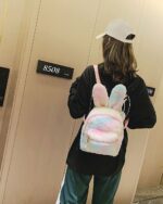A pink Rabbit Ears Plush Backpack is worn by a person. It features soft plush material and rabbit ears.
