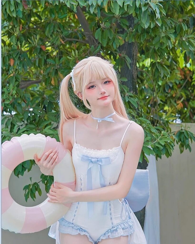 Model wearing a blue Lolita Inspired Swimwear outfit with a pink floatie.