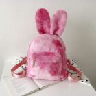 Pink Rabbit Ears Plush Backpack on a table with a book.