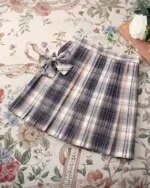 JK Plaid Skirt, a pleated summer skirt with a bow tie detail on a floral background.