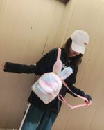 Pink and white Rabbit Ears Plush Backpack shown being carried by a person.