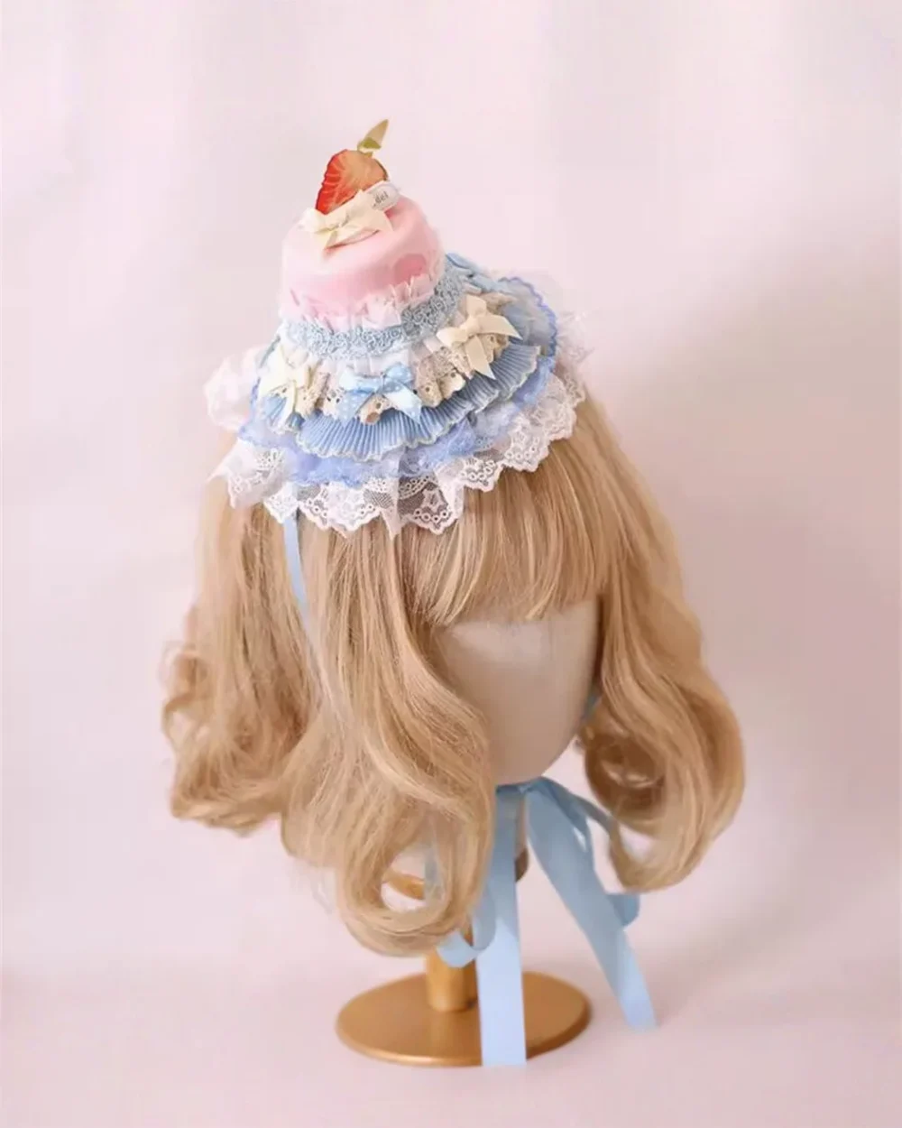 Sweet Lolita Hairpin adorns blonde wig, featuring a miniature cake and ruffled blue lace design.