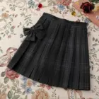 A black JK Plaid Skirt with a bow, displayed on a floral background.