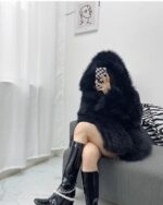 Woman wearing a Thick Fluffy Faux Fur Coat, black boots, and a modern interior setting.