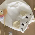 Cream Neko Hoodie laid out on a wooden surface with other plush toys.