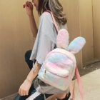 A pink and blue Rabbit Ears Plush Backpack worn by a person.