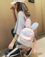 A pink and blue Rabbit Ears Plush Backpack worn by a person.