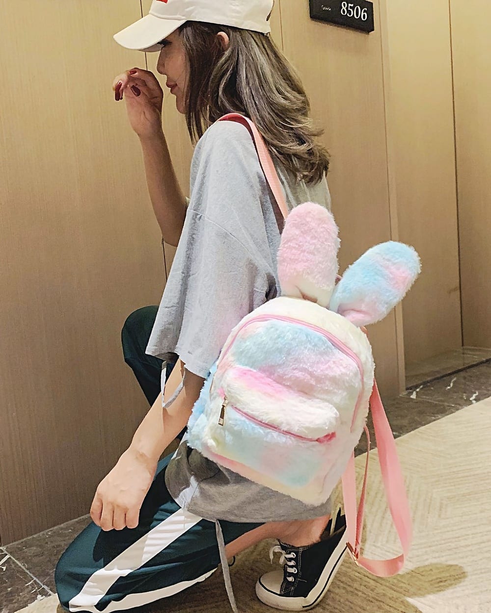 A pink and blue Rabbit Ears Plush Backpack worn by a person.