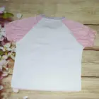 White Sugarbunnies T-Shirt with pink sleeves, on wooden background.