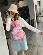 Pink Rabbit Ears Plush Backpack worn by a woman in a public space.
