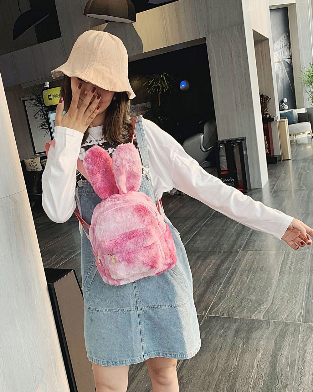 Pink Rabbit Ears Plush Backpack worn by a woman in a public space.