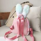 Pink Rabbit Ears Plush Backpack with shoulder straps, displayed on a sofa.