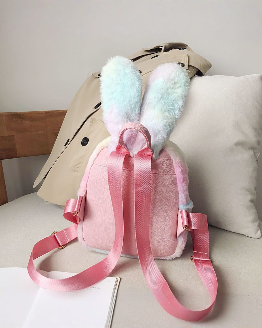 Pink Rabbit Ears Plush Backpack with shoulder straps, displayed on a sofa.