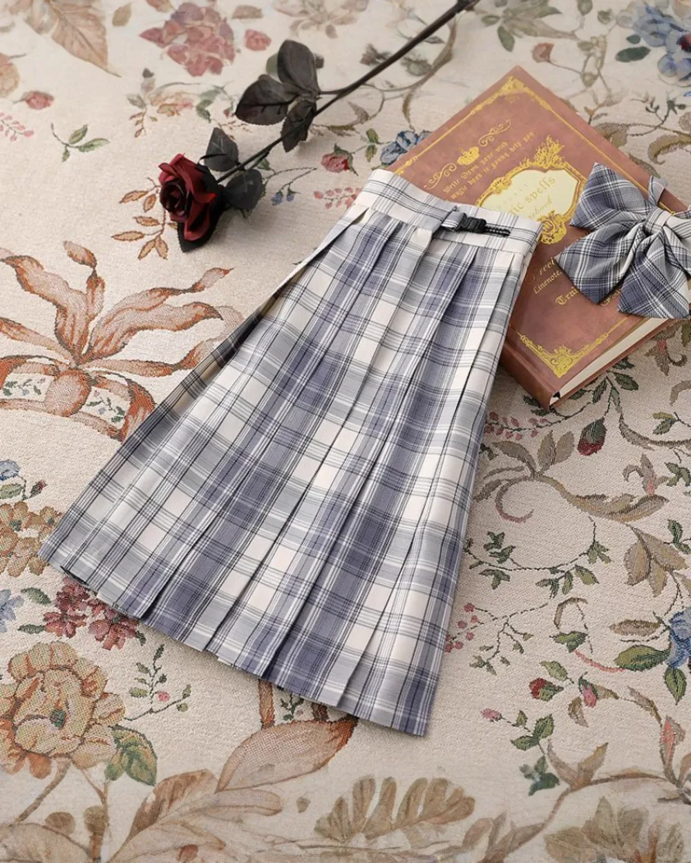 A JK Plaid Skirt, featuring a blue and gray plaid pattern, shown on a patterned background.