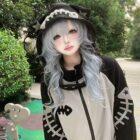 Person wearing a Fish Bone Hoodie and a hat with a skull design.