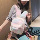 A pink and white Rabbit Ears Plush Backpack carried by a woman.