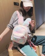 A pink and white Rabbit Ears Plush Backpack carried by a woman.