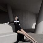 Woman wearing Anime Nun Costume - Halloween Edition, black robe, gloves, and veil.