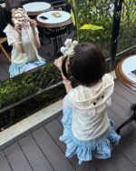 Woman wearing a blue Kuma Zip Up Hoodie - Jojifuku Hoodie at an outdoor cafe.