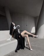 Woman wearing Anime Nun Costume - Halloween Edition, black gown, gloves, and heels.