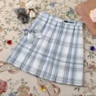A light blue and white JK Plaid Skirt with a tie detail, displayed on a patterned rug.