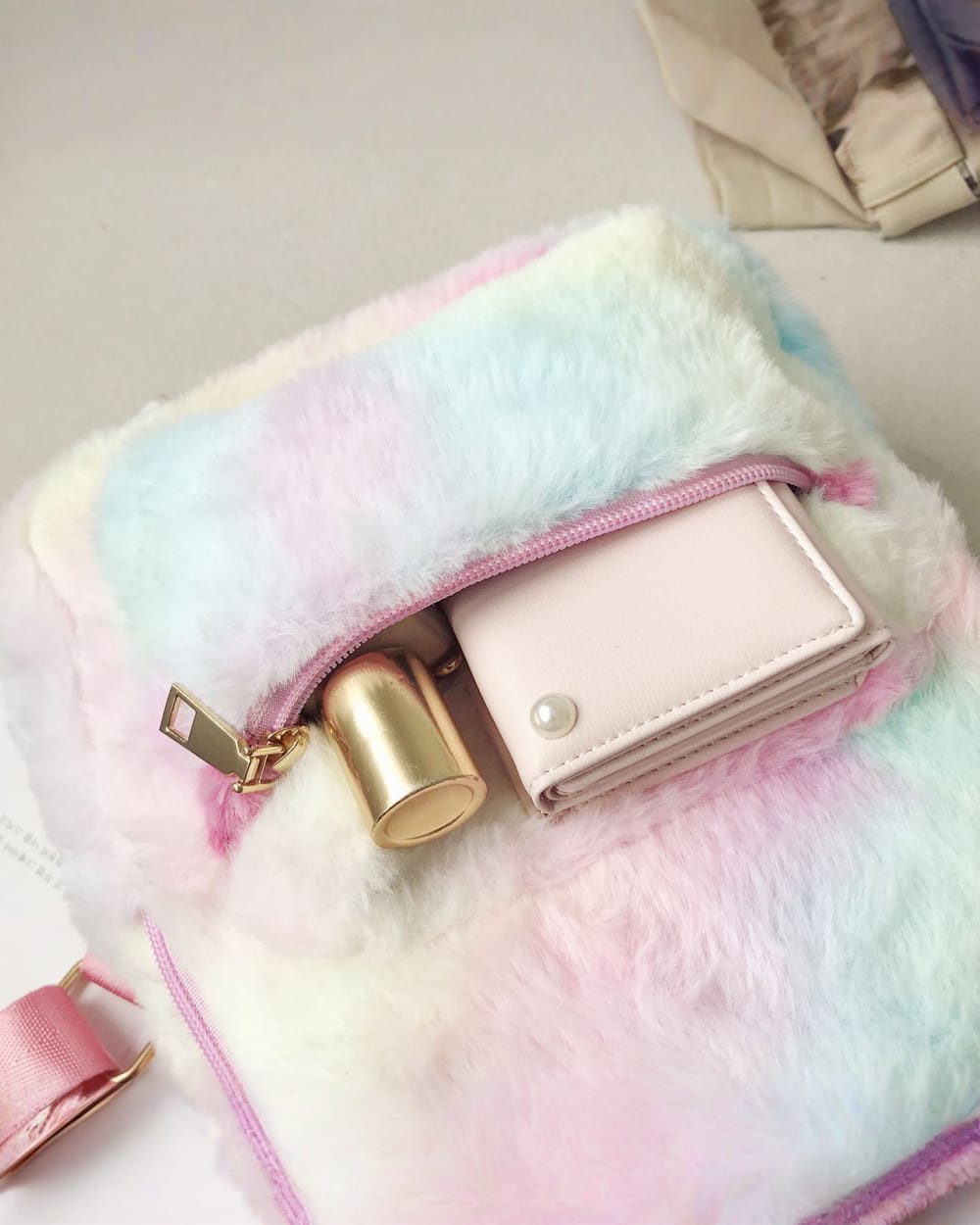 Close-up of a colorful Rabbit Ears Plush Backpack with a wallet and zipper.