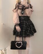 Woman wearing a Jirai Kei Blouse with ruffles and lace details, paired with a plaid skirt and accessories.
