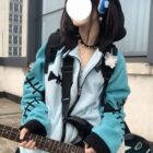Person wearing a teal Fish Bone Hoodie with black accents and star details, playing a guitar.