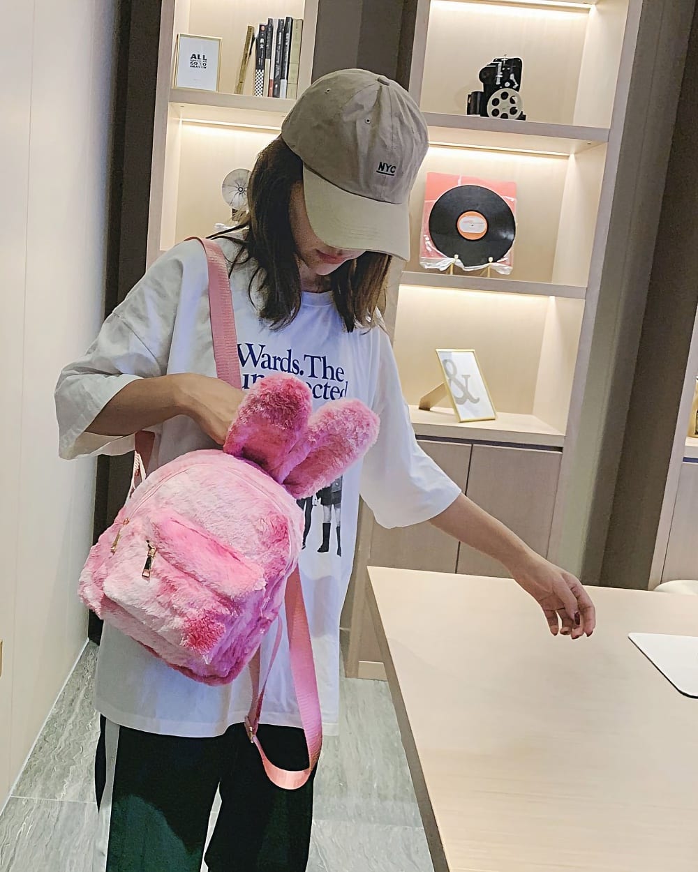 Pink Rabbit Ears Plush Backpack carried by a woman in a store.