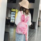 Pink Rabbit Ears Plush Backpack worn by a woman in a public space.