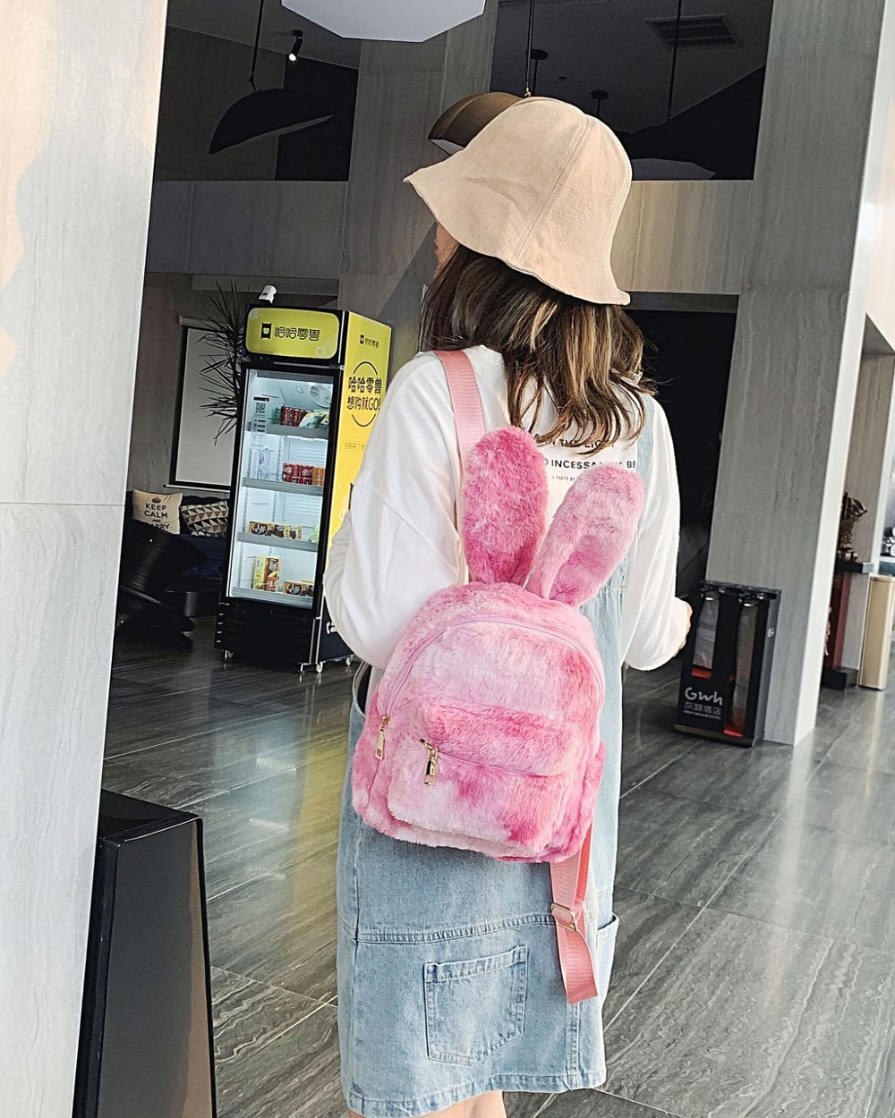 Pink Rabbit Ears Plush Backpack worn by a woman in a public space.