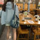 Person wearing a blue Preppy Aesthetic Hoodie in a Korean BBQ restaurant.