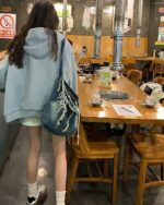 Person wearing a blue Preppy Aesthetic Hoodie in a Korean BBQ restaurant.
