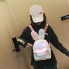 A pink and white Rabbit Ears Plush Backpack is worn by a person.
