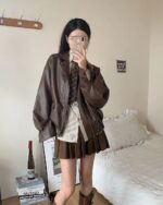 Woman posing with a brown Korean Style Jacket, preppy aesthetic, layered outfit.