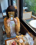 Person wearing a Jojifuku Hoodie at a cafe, featuring a bear graphic.