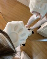White Fluffy Bear Paw Hoodie shown on a wooden floor.