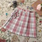 Pink JK Plaid Skirt with bow, displayed on a floral background.