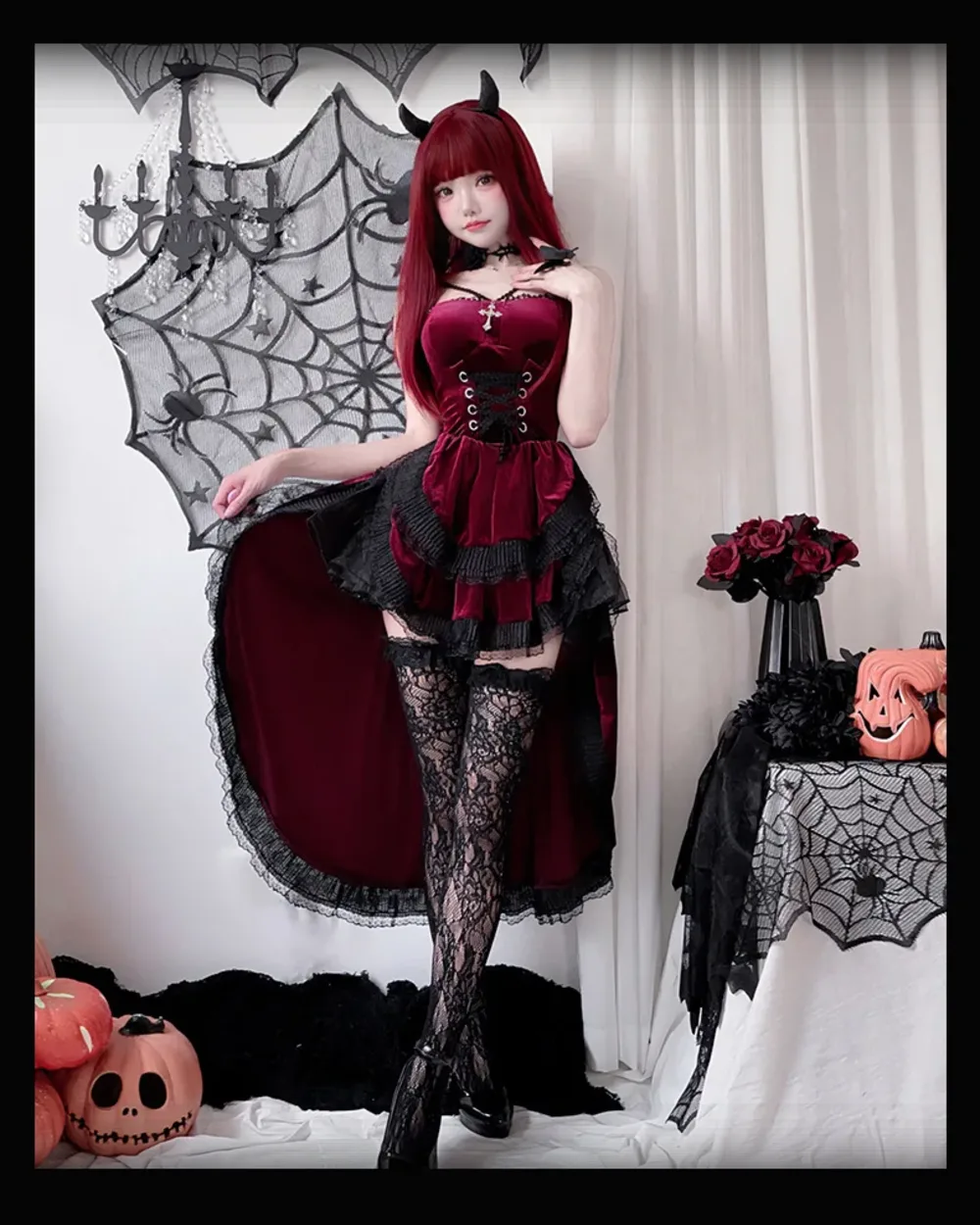 Woman wearing a Dark Nun Dress, burgundy corset and skirt with lace stockings and devil horns.
