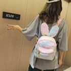 A pink and white Rabbit Ears Plush Backpack worn by a person.