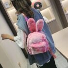 Pink Rabbit Ears Plush Backpack shown as a casual shoulder bag carried by a person.