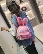 Pink Rabbit Ears Plush Backpack shown as a casual shoulder bag carried by a person.
