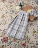 A JK Plaid Skirt, featuring a pleated design, rests on a floral patterned surface.