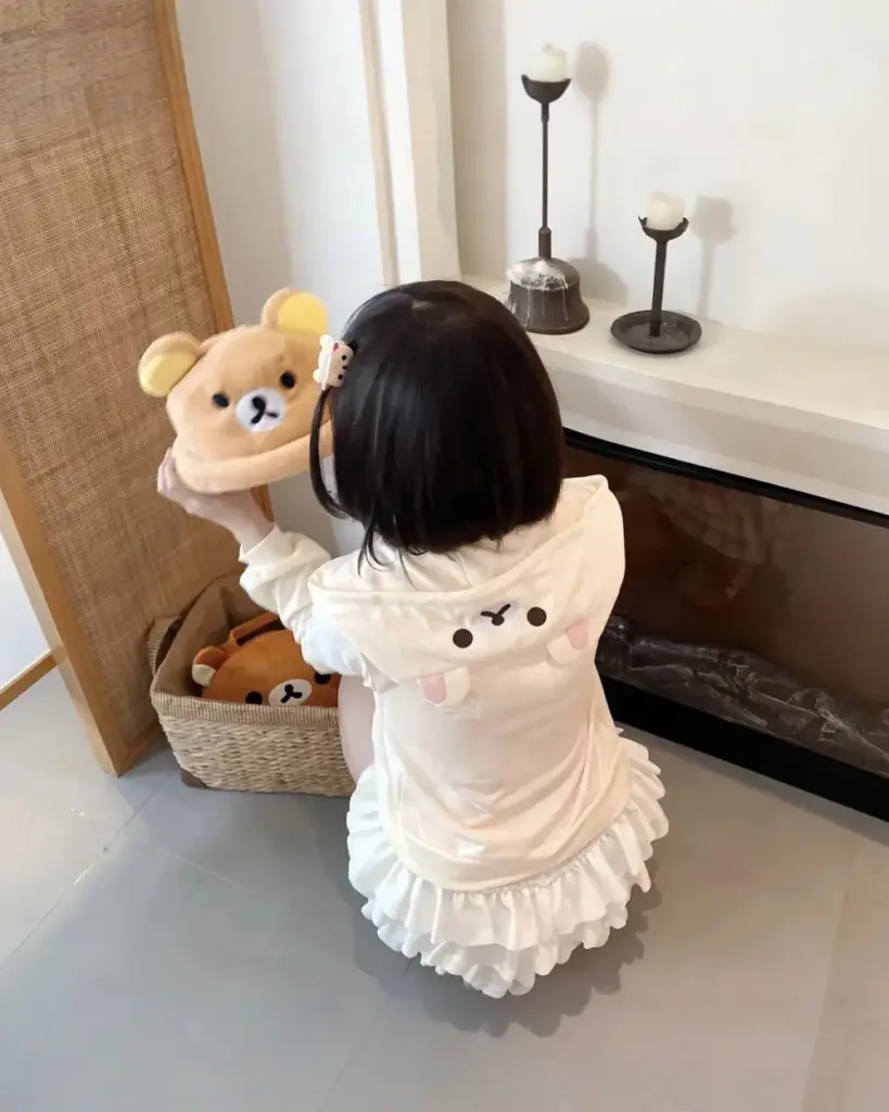 Child wearing a white Jojifuku Hoodie with Rilakkuma print, featuring a zipper and ruffled hem.