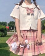 Woman wearing a pink and red JK Plaid Skirt with a white blouse and bow.