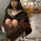 Person wearing a College Style Zip Up Hoodie - Preppy Aesthetic, brown puffer jacket, and a blue baseball cap in a restaurant.