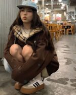 Person wearing a College Style Zip Up Hoodie - Preppy Aesthetic, brown puffer jacket, and a blue baseball cap in a restaurant.