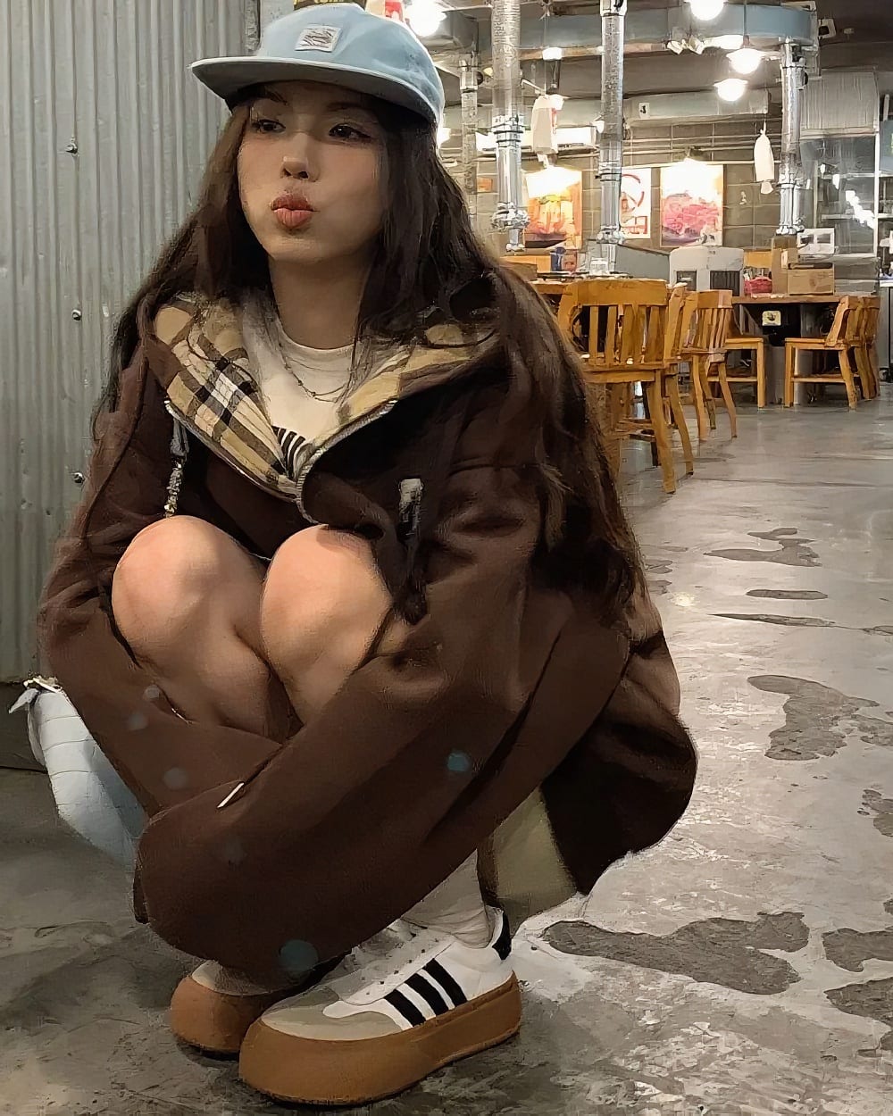 Person wearing a College Style Zip Up Hoodie - Preppy Aesthetic, brown puffer jacket, and a blue baseball cap in a restaurant.