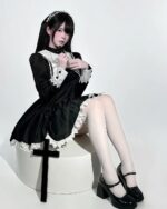 Woman wearing a black Gothic Nun Dress with white lace details, featuring a cross accessory.